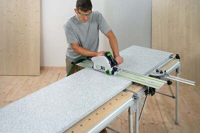 Person using Festool track saw on multifunction table cutting large panel in woodworking tools and tool stands collection