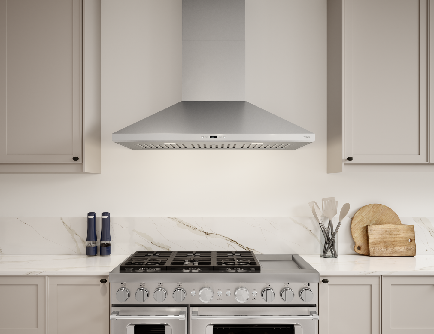 Stainless steel wall mounted range hood above stainless steel gas stove in modern kitchen with light cabinetry
