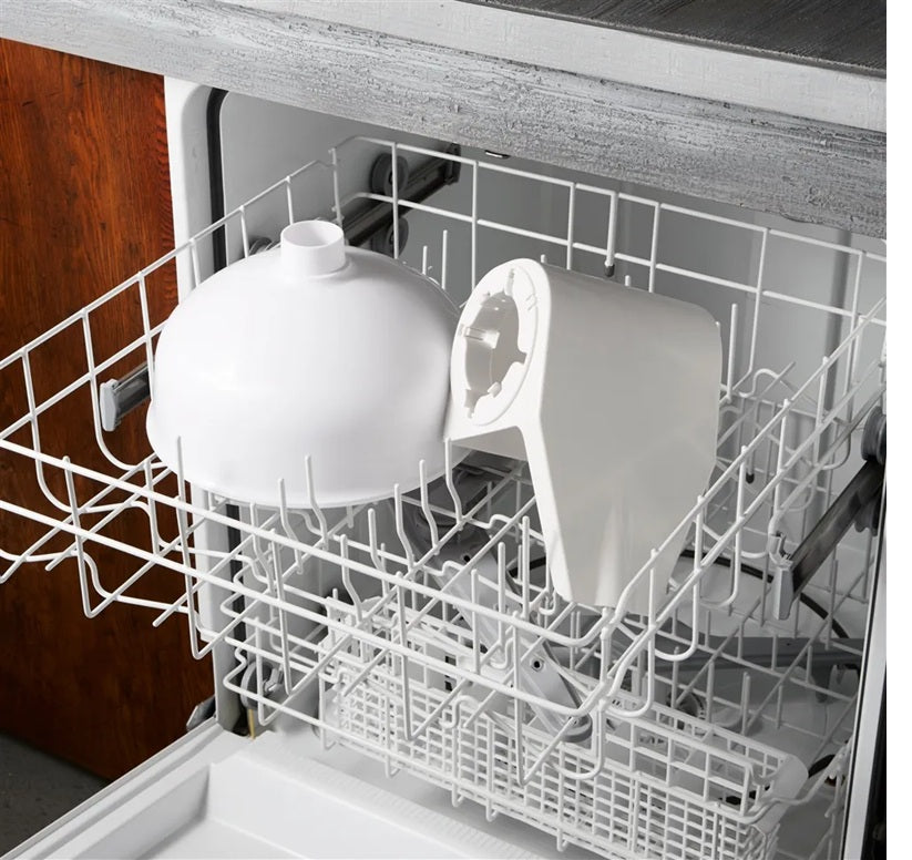 White plastic components of an electric kitchen strainer placed in the open rack of a dishwasher inside a kitchen appliance setting
