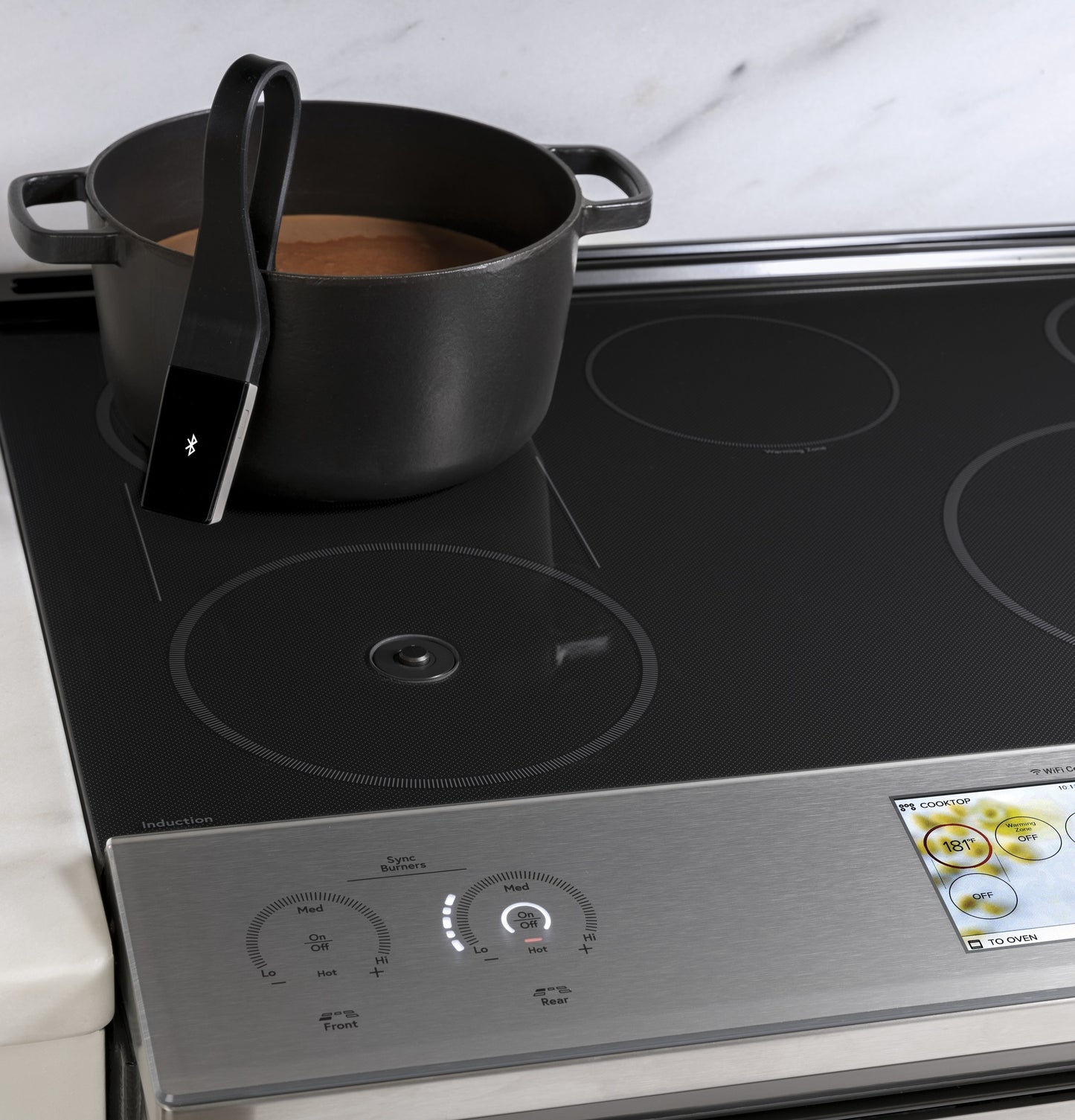 Pot with stew on black induction cooktop surface of front-control slide-in range with digital display and controls