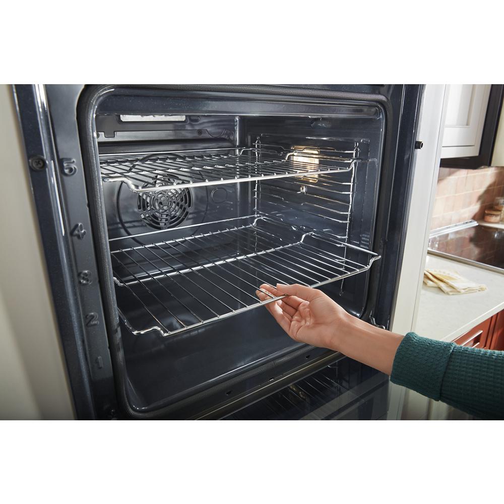 Hand adjusting chrome oven rack inside a 24-inch smart single wall oven with true convection feature