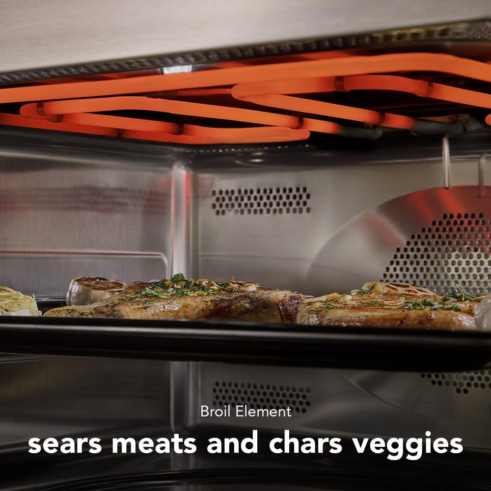 Broil element glowing orange above roasting pan with seasoned meat and vegetables inside stainless steel oven interior