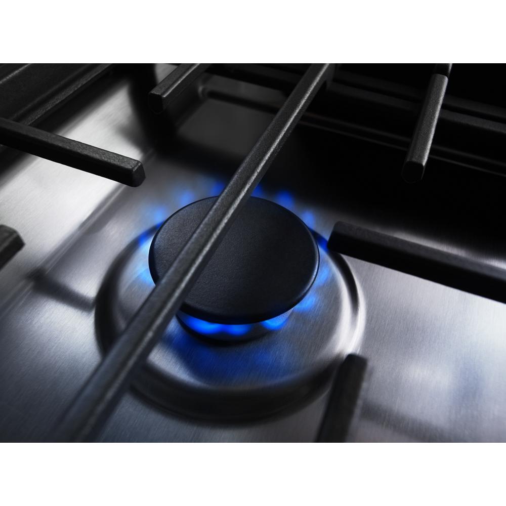 Close-up of blue gas flame burner on stainless steel cooktop from KitchenAid ranges and appliances collection