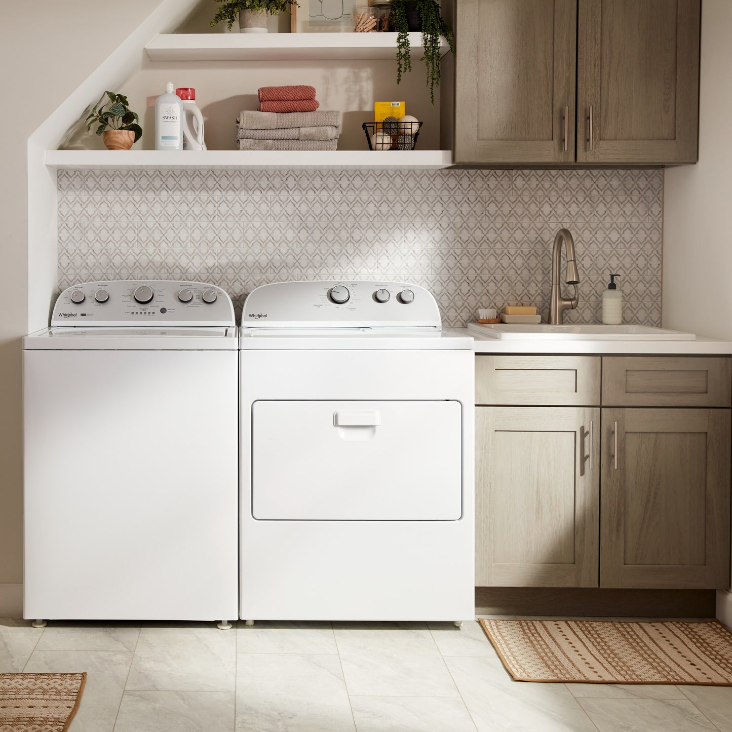 White top load gas dryer with control knobs next to a matching washer in a modern laundry room setting