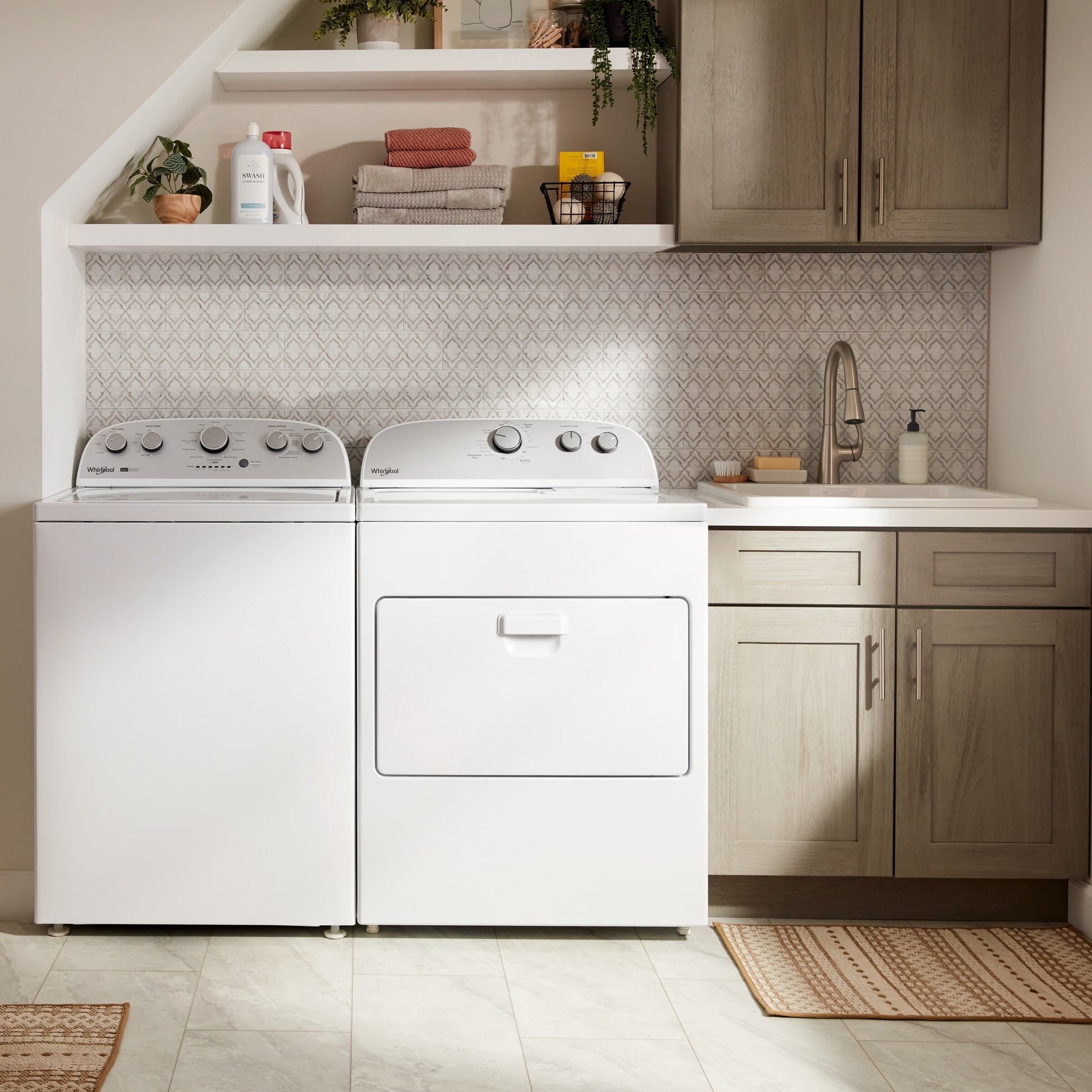White top load gas dryer with control knobs next to a matching washer in a modern laundry room setting