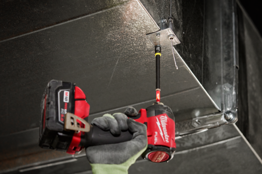 Person using red Milwaukee impact driver with magnetic nut driver attachment fastening metal ductwork in home improvement setting