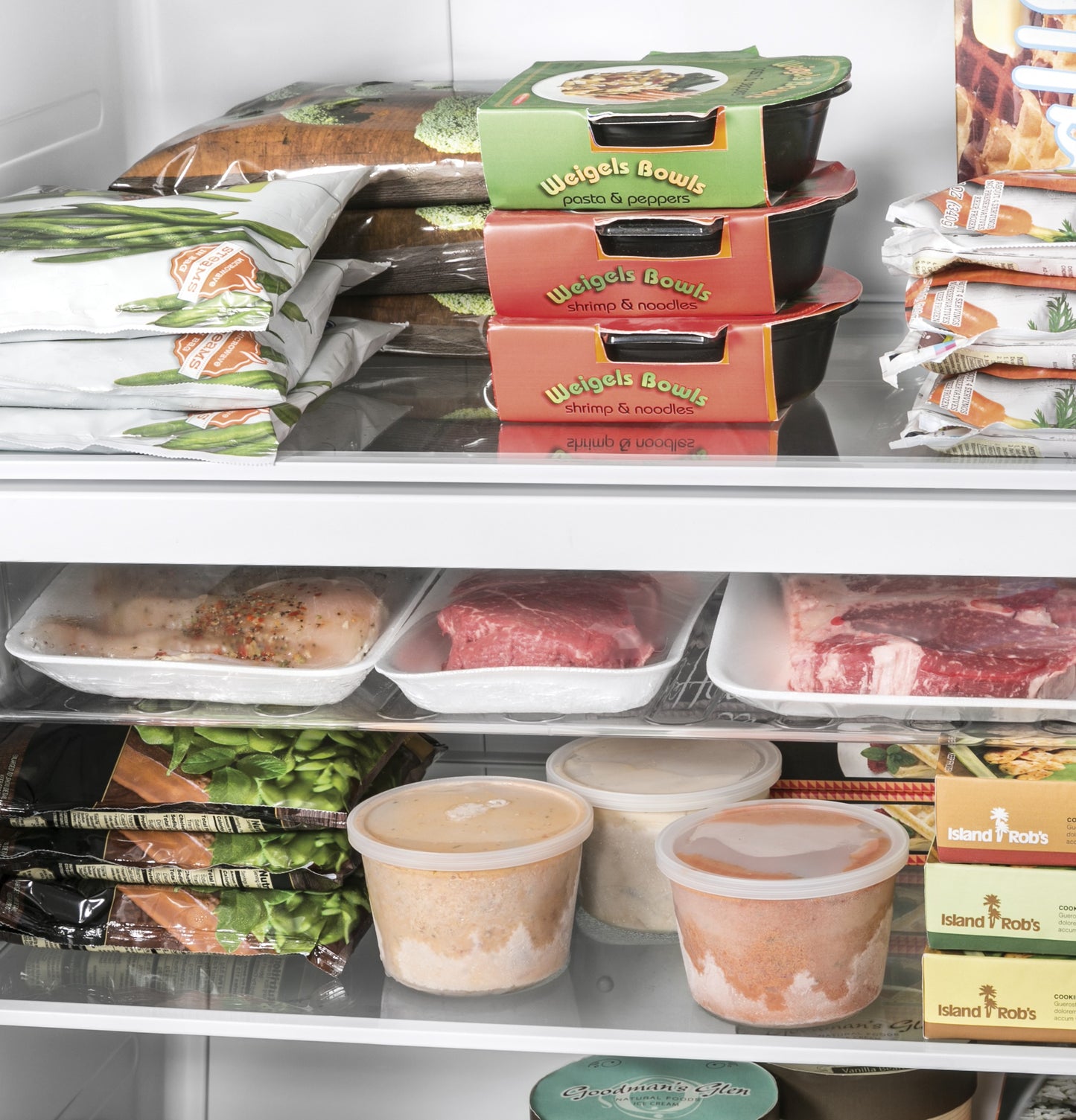 Interior view of an upright freezer stocked with frozen meals, raw meat, and packaged frozen vegetables in appliances collection