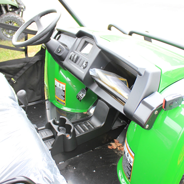 Interior view of green utility vehicle featuring dashboard, steering wheel, storage compartments, and cup holders for outdoor tasks