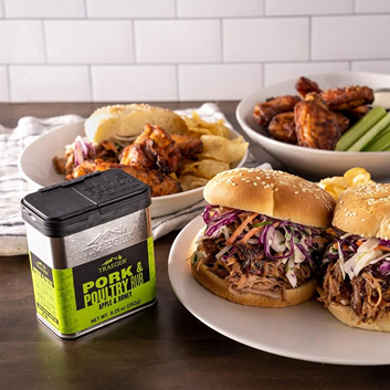 Metal container of Traeger pork and poultry rub beside pulled pork sandwiches and chicken wings for grilling and outdoor living
