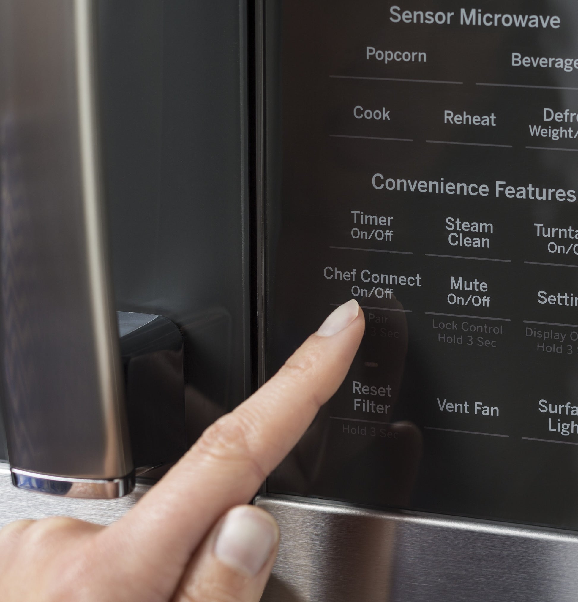 Close-up of finger pressing Chef Connect button on stainless steel sensor microwave control panel from kitchen appliances collection