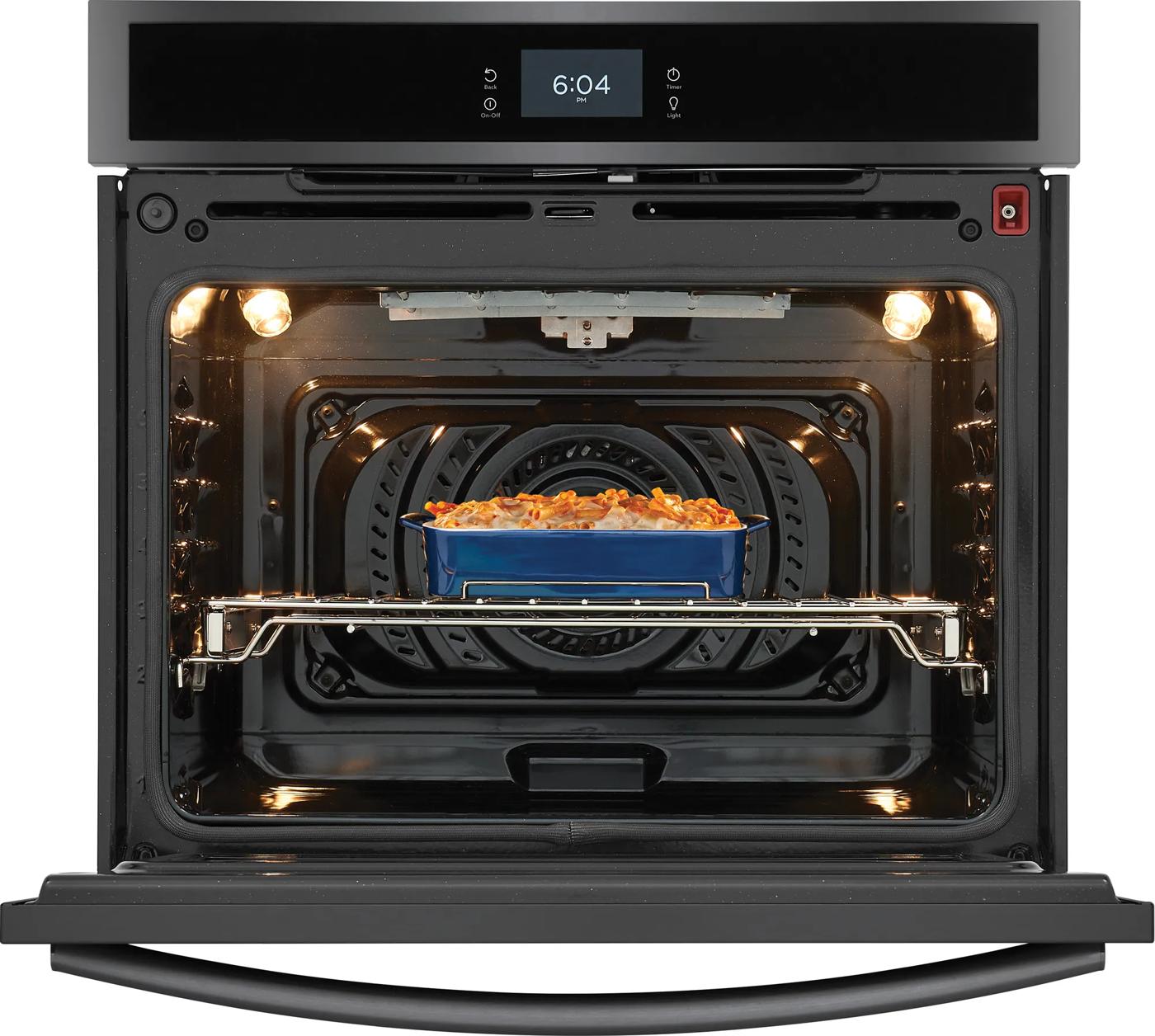 open stainless steel wall oven with digital clock and convection fan baking casserole dish inside