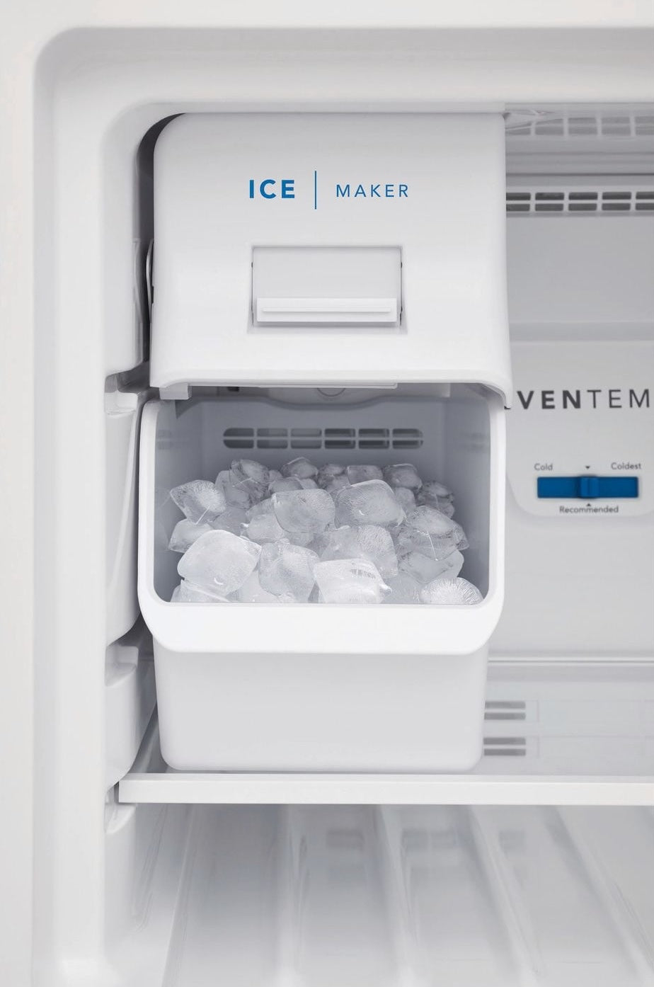 White top mount ice maker installed inside refrigerator with clear ice cubes in collection of kitchen appliances