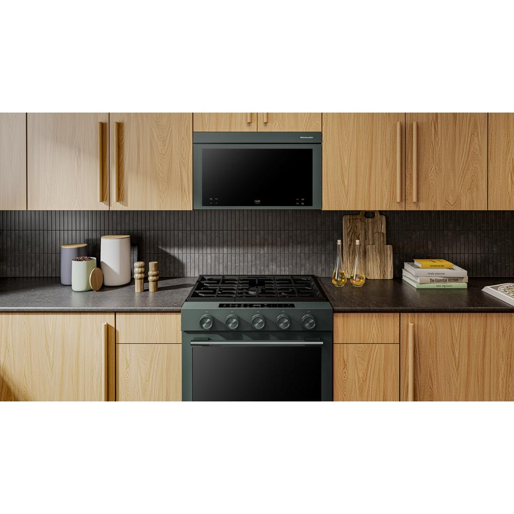 Sleek black multifunction over-the-range microwave installed flush with wood cabinets above gas stove in modern kitchen