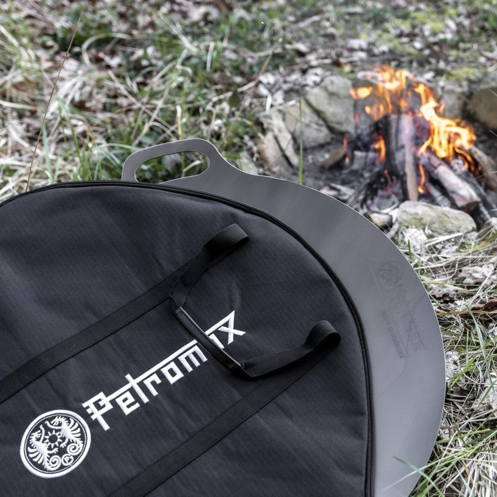 Black durable transport bag with handles for safely carrying griddle and fire bowl in outdoor camping setting