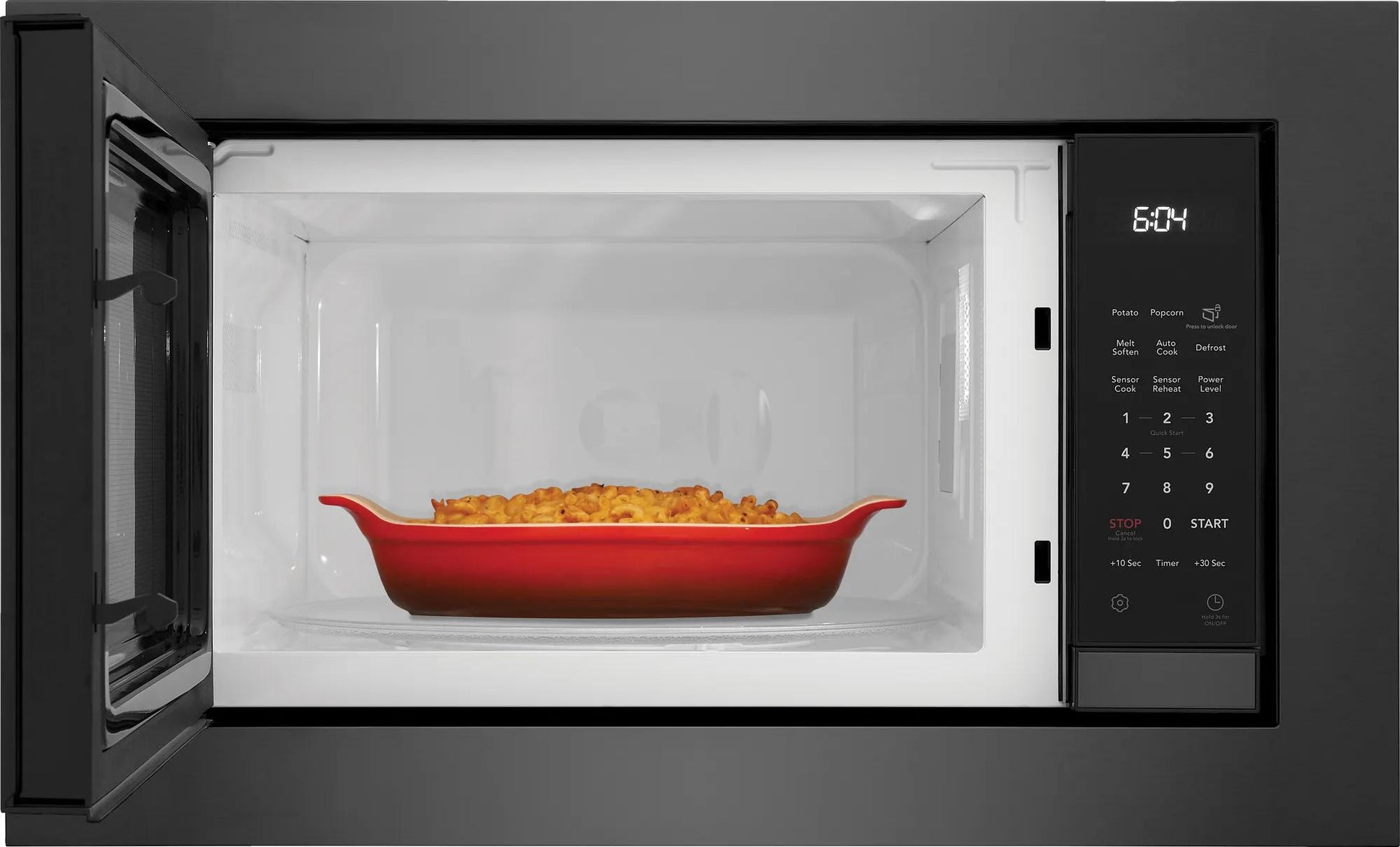 Built-in black microwave with digital control panel and red casserole dish inside in kitchen appliances collection