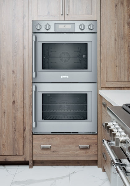 Built-in stainless steel 30-inch double wall oven with digital controls integrated into wood cabinetry in modern kitchen appliances collection