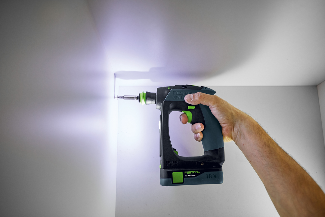 Hand holding Festool 18V cordless drill with LED light drilling into corner for home improvement tasks