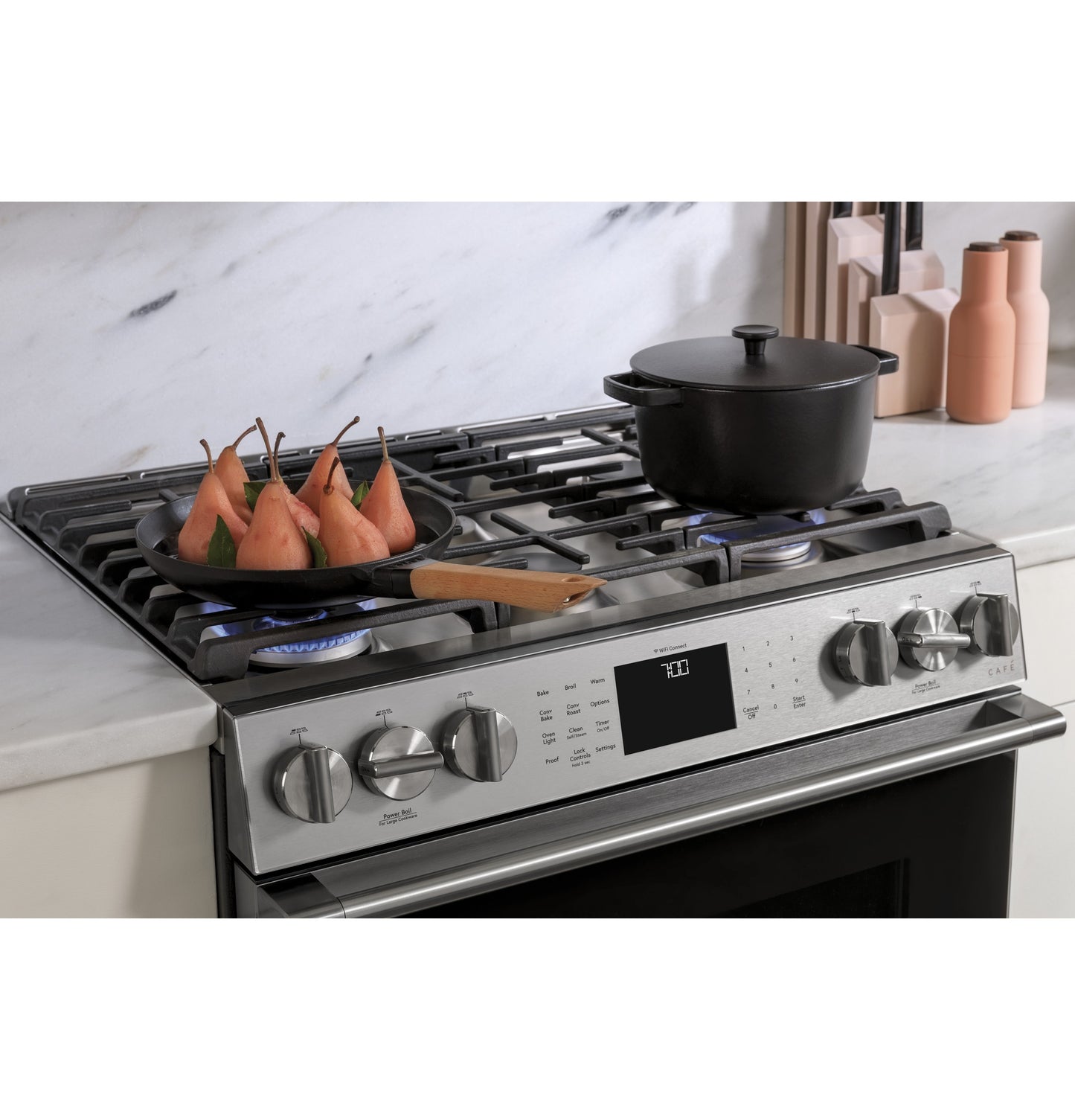 Front control platinum glass slide-in gas range with pots cooking on burners in modern kitchen setting