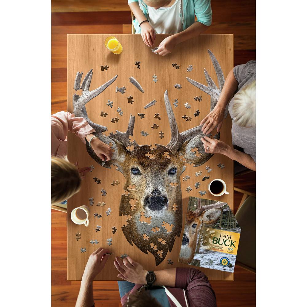 Four people assembling a shaped jigsaw puzzle of a buck head on a wooden table with drinks nearby in puzzles collection