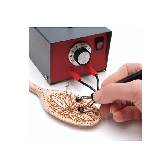 Hand using a pyrography tool connected to a temperature control unit to burn a floral design on a wooden spoon