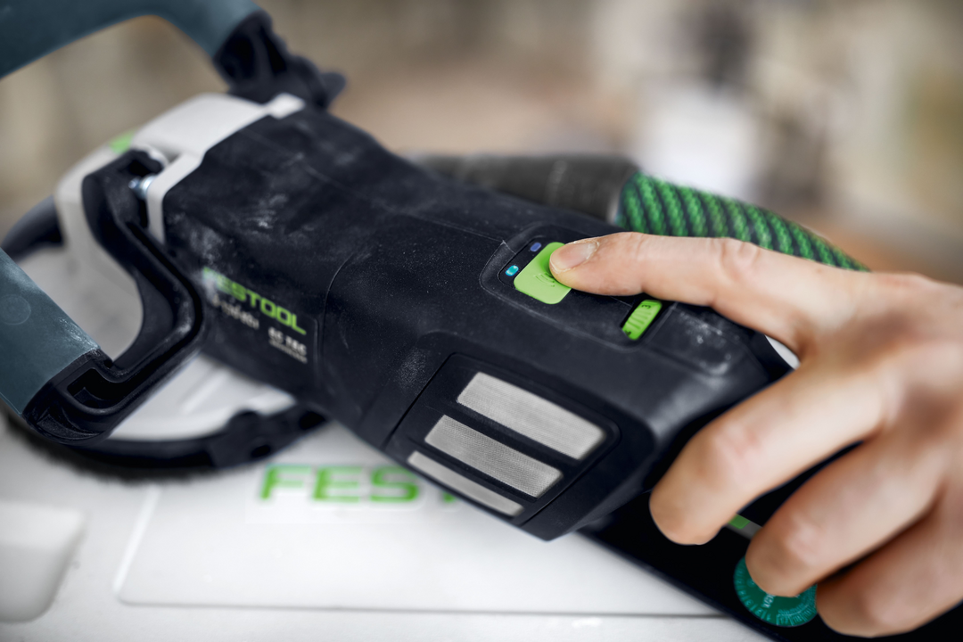 Person pressing power button on Festool diamond grinder with green and black ergonomic grip for home improvement tasks