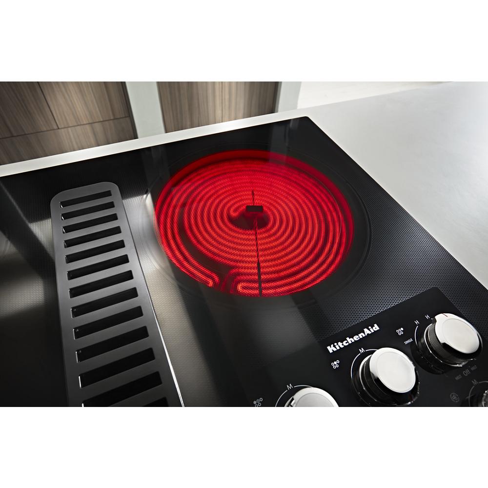 Electric cooktop with glowing heating element and integrated downdraft vent from KitchenAid cooktops collection
