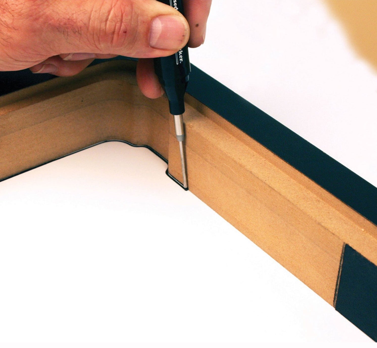 Hand using long nose marker to draw precise black line on light wood molding for home improvement projects