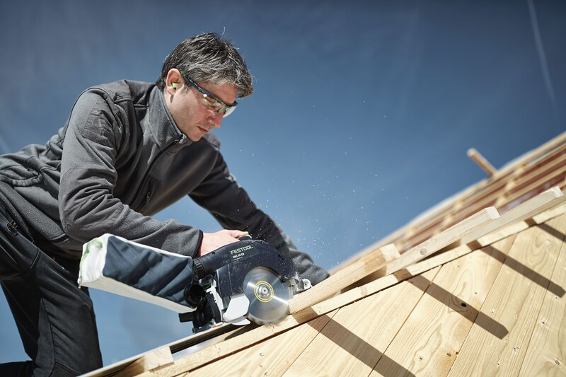 Man wearing safety glasses using Festool track saw with dust bag to cut angled wooden boards outdoors in tool accessories collection