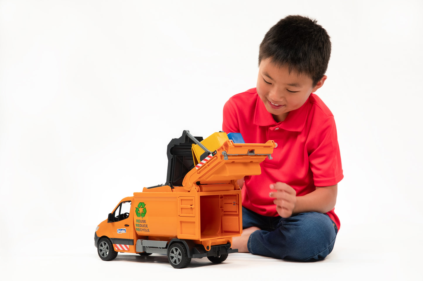 Boy in red shirt playing with orange toy MB Sprinter garbage truck with open rear compartment for tools and home improvement play