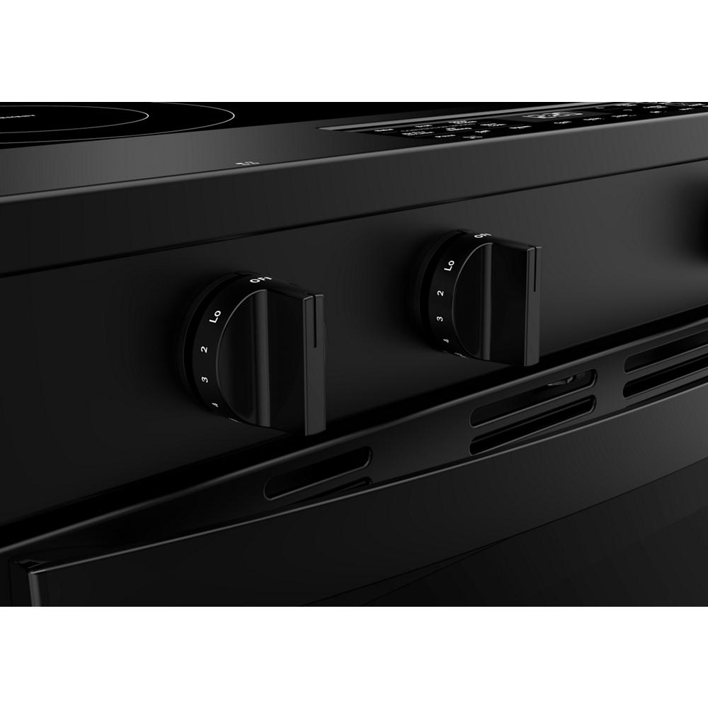 Close-up of black electric range control knobs with numeric heat settings on front panel in kitchen appliances collection