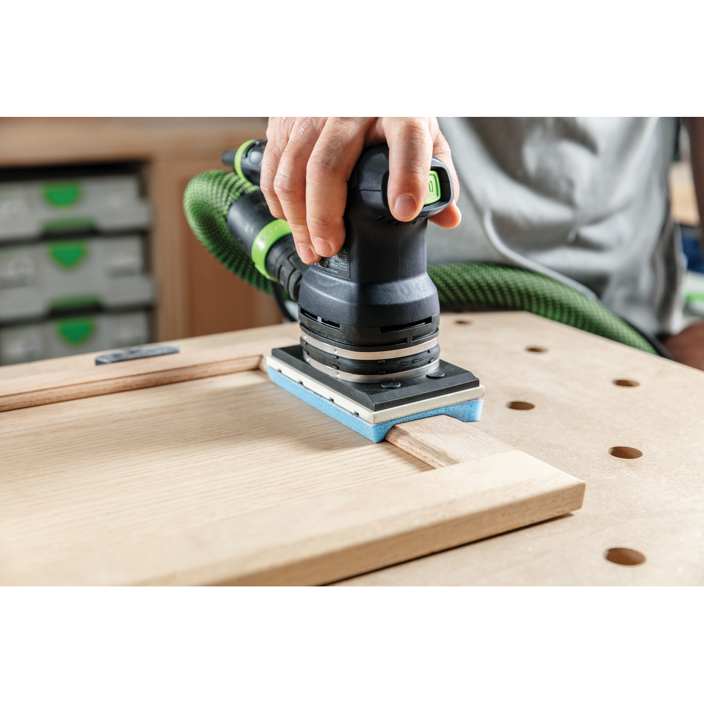 Handheld power sander with blue foam-backed abrasive smoothing wooden door panel in home improvement and tool accessories setting