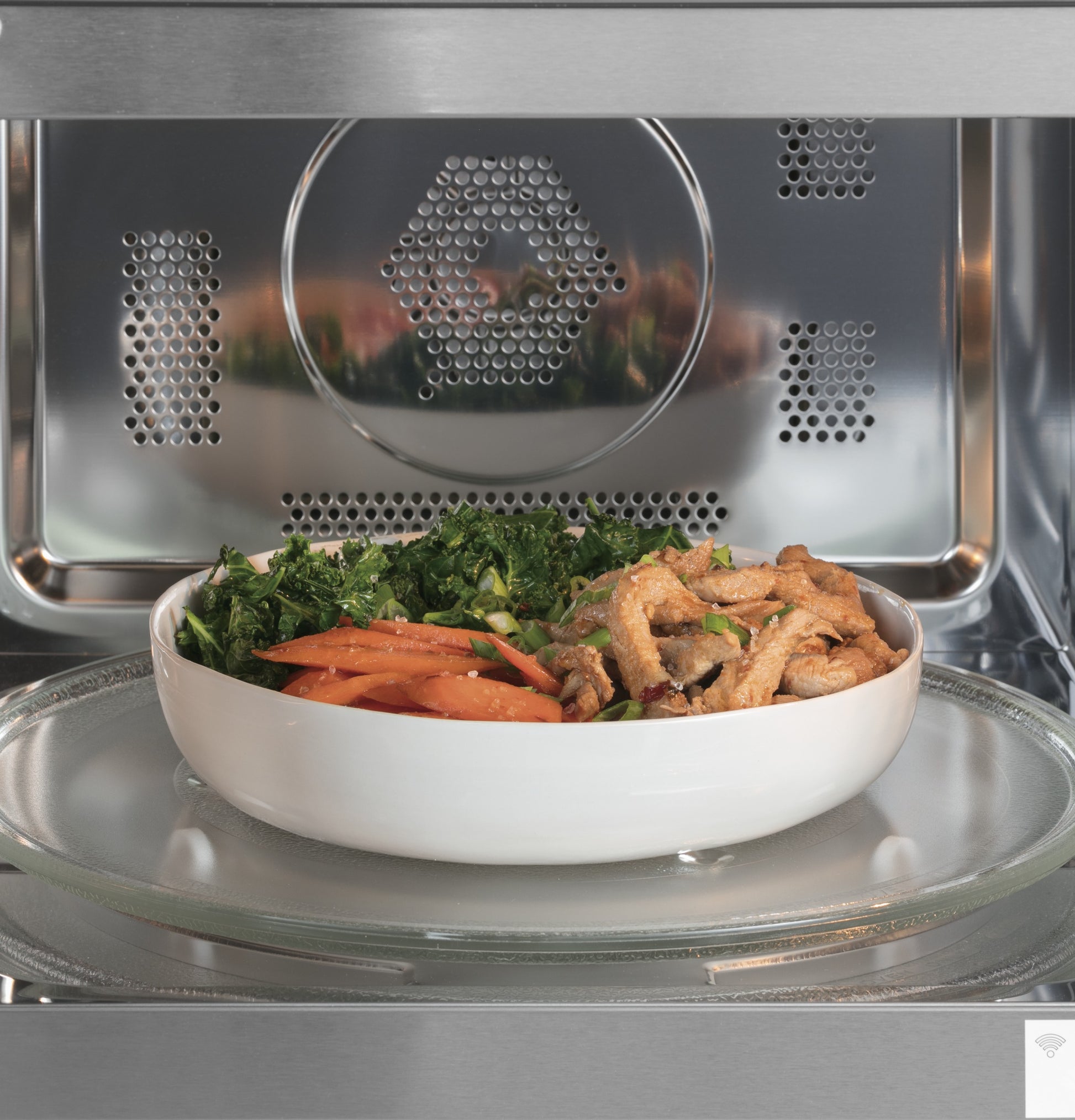 White bowl with cooked vegetables and crispy strips inside stainless steel smart countertop microwave oven from Microwaves collection