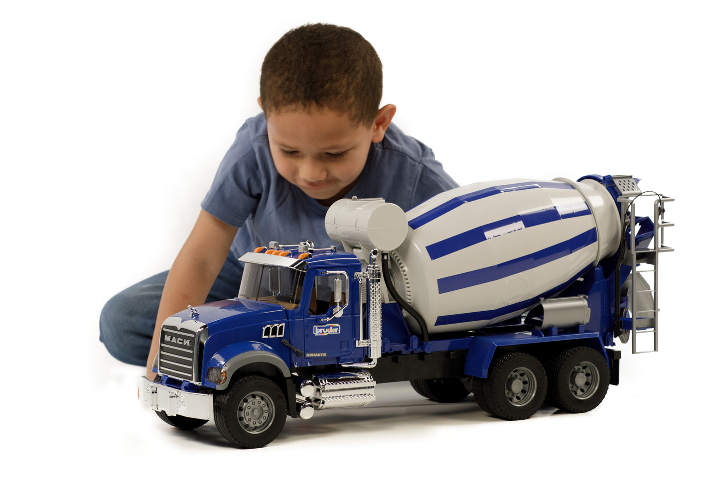 Young boy playing with a detailed blue Bruder 1:16 scale Mack Granite cement mixer truck model