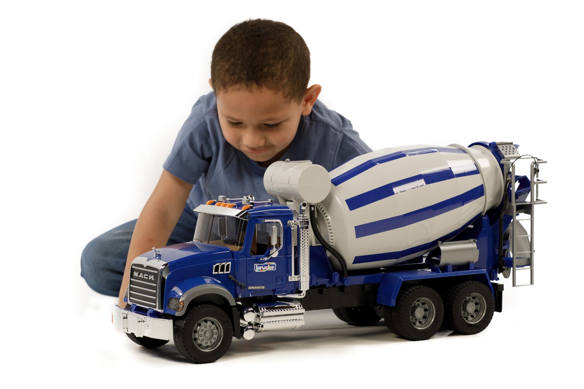 Young boy playing with a detailed blue Bruder 1:16 scale Mack Granite cement mixer truck model