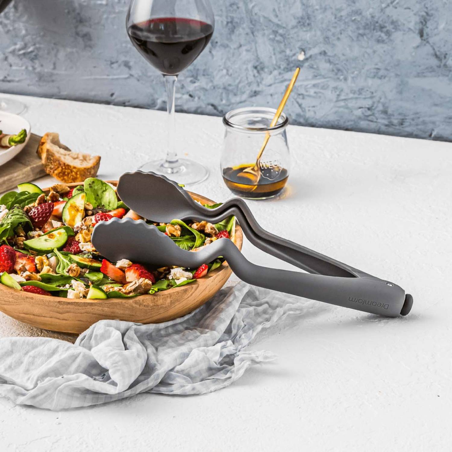Gray 10.5-inch Dreamfarm kitchen tongs resting on wooden bowl with mixed salad in kitchenware setting