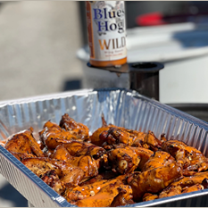 Aluminum tray filled with glazed chicken wings cooked with savory sauce for outdoor grilling and home cooking