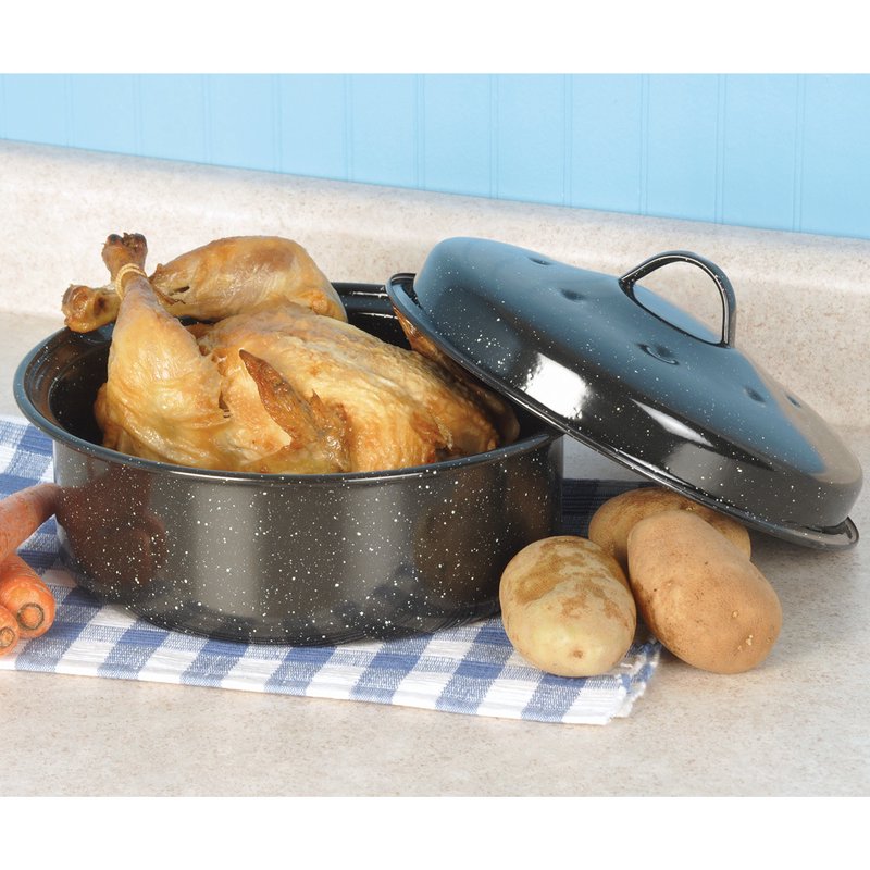 Black covered round roaster with porcelain enamel finish, shown with roasted chicken and potatoes on kitchen countertop
