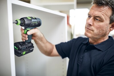 Man using Festool cordless drill with brushless motor and FastFix system on white furniture during home improvement tasks
