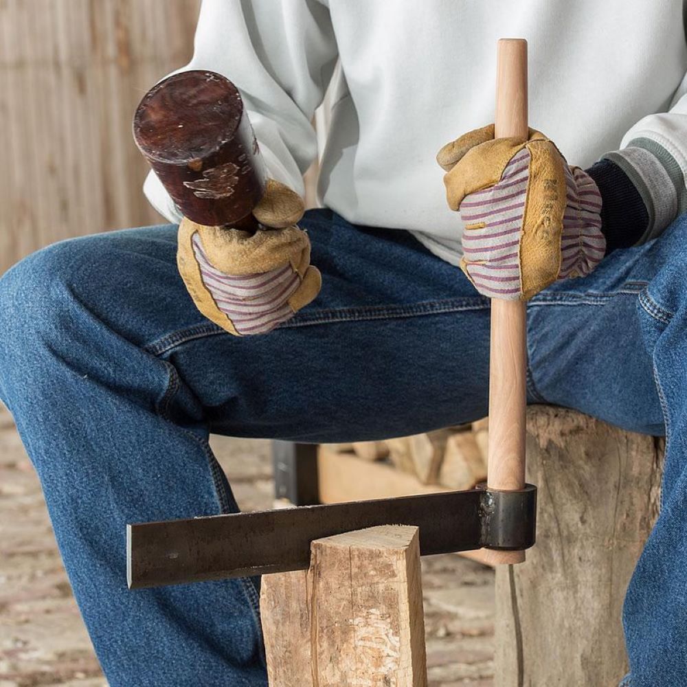 Person wearing gloves holding wood splitting froe and wooden mallet, tool for home improvement under $50 collection