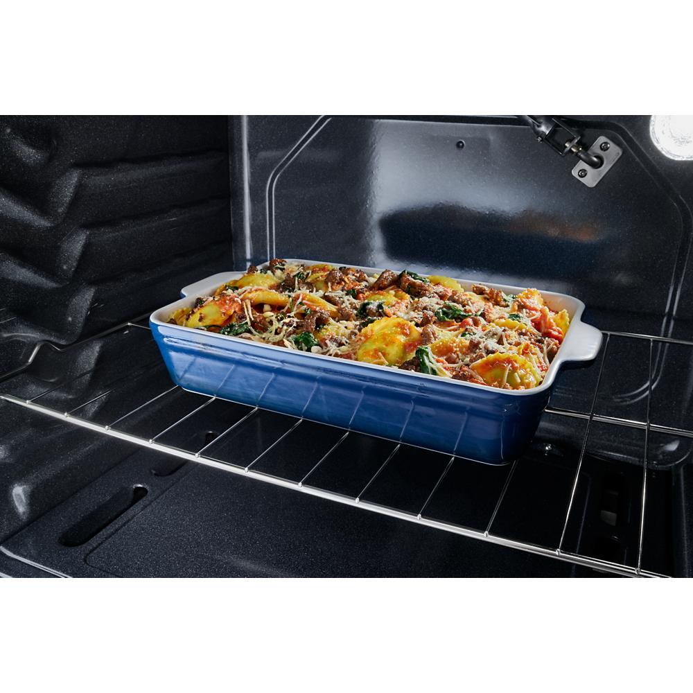 Blue ceramic baking dish with casserole cooking inside an electric oven for home improvement and kitchenware.