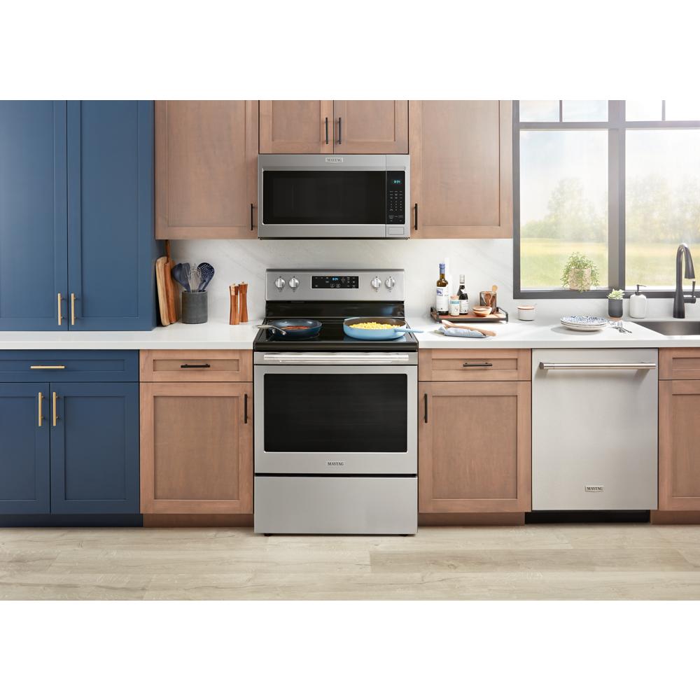 Modern stainless steel electric range with dual burners cooking food, integrated into kitchen cabinetry and appliances setting
