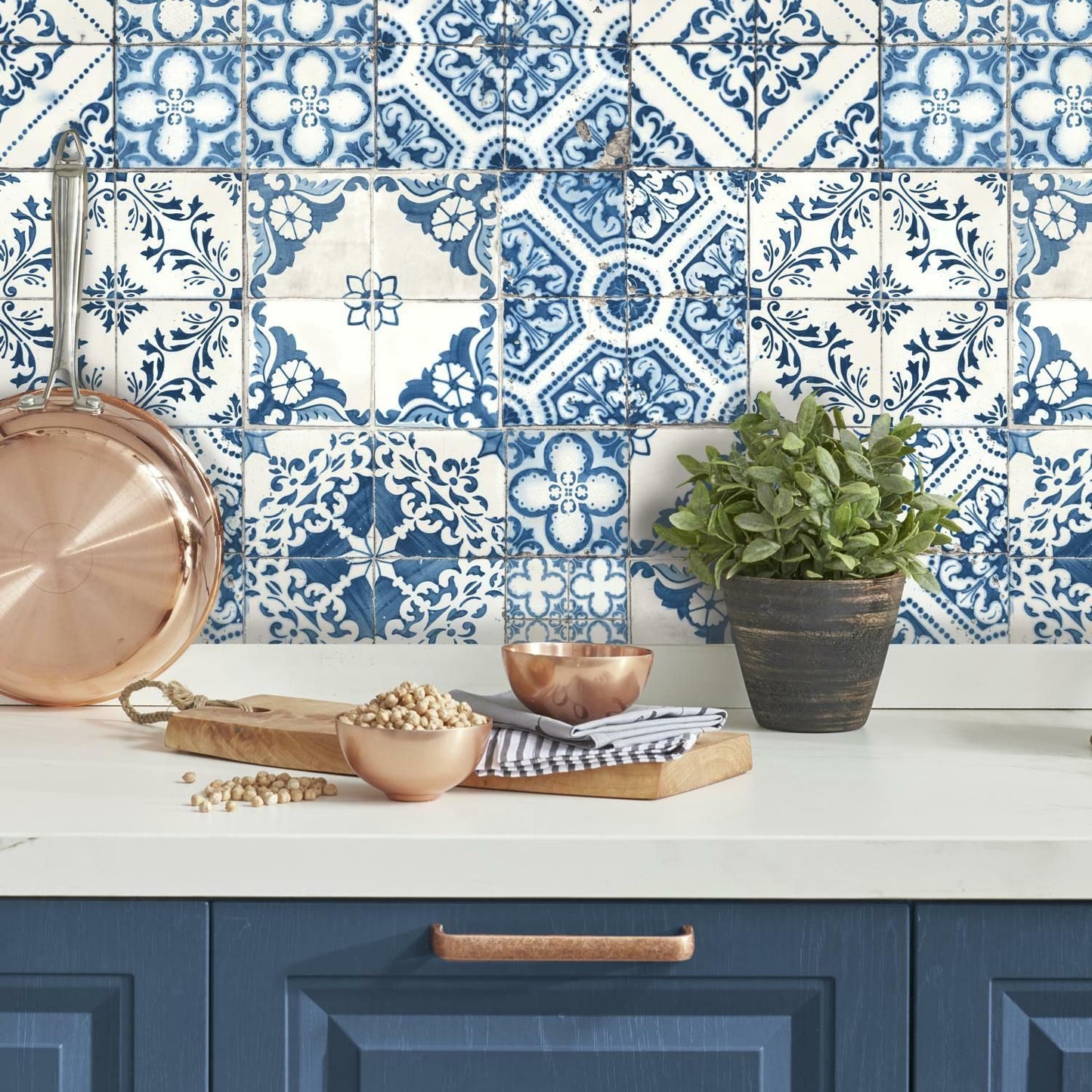 Blue and white Mediterranean style peel and stick wallpaper in kitchen with copper cookware and green potted plant