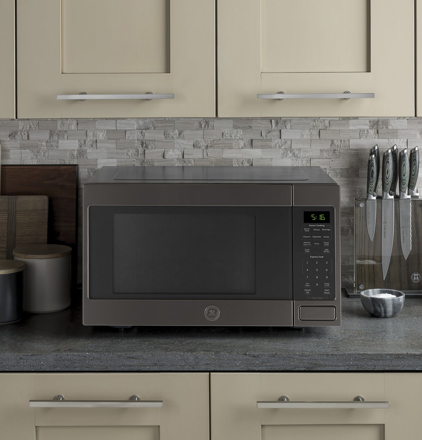 Countertop microwave oven in dark stainless steel with digital control panel in modern kitchen setting