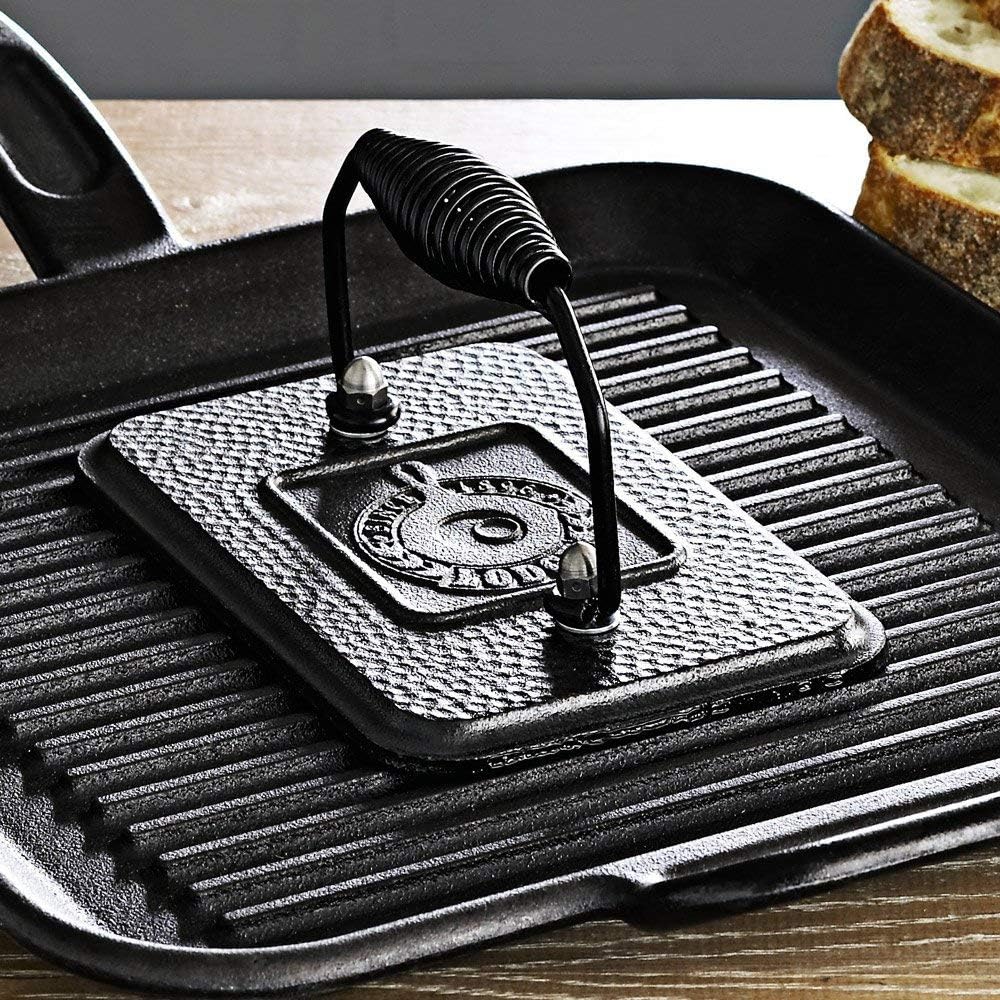 Rectangular cast iron grill press with coil handle on ribbed cast iron griddle, ideal for kitchenware and gadgets under $50 collection