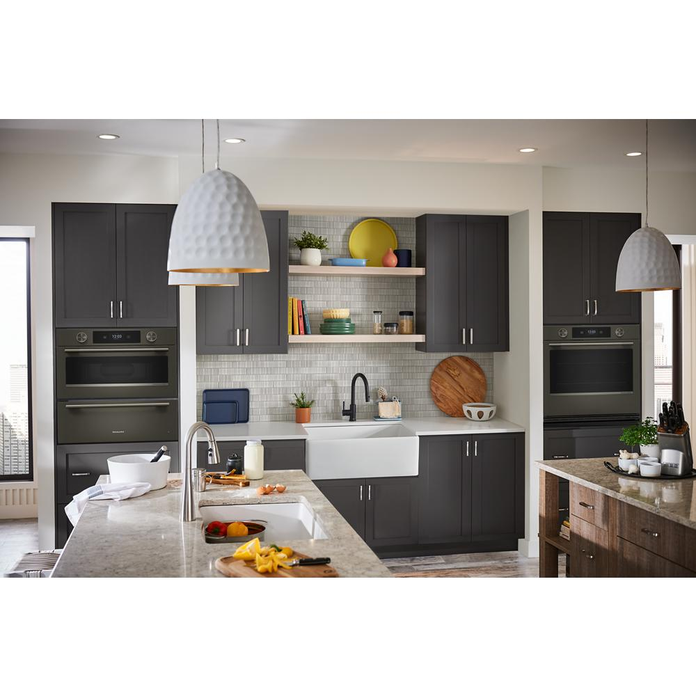 Modern kitchen with dark gray cabinetry, farmhouse sink, built-in wall ovens, and marble countertops in appliances category