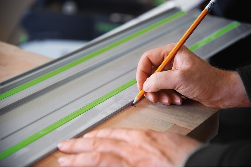 Person marking wood along a 55-inch aluminum guide rail with green anti-slip strips for precise woodworking tools