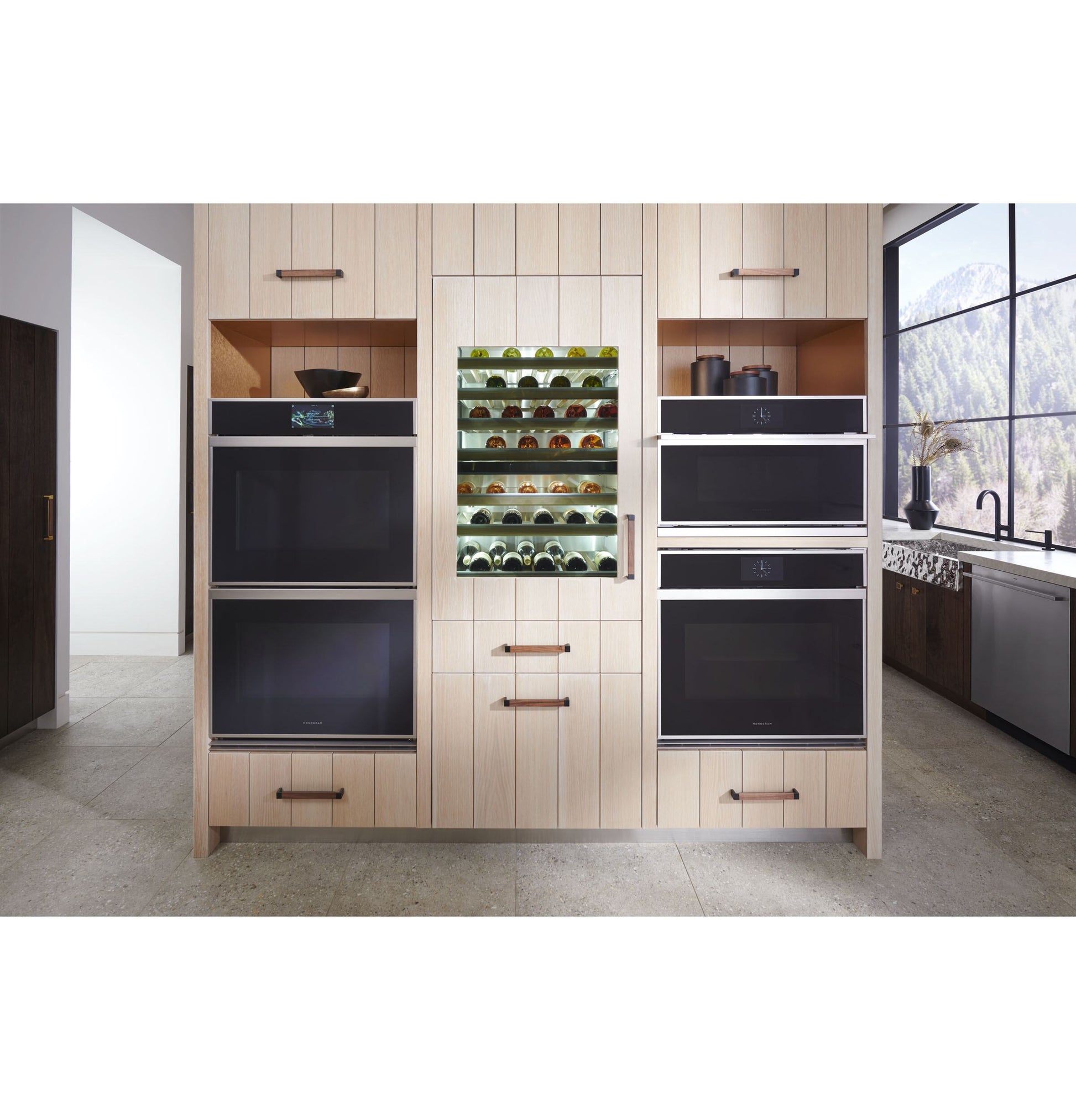 Built-in stainless steel wall ovens and wine cooler integrated into light wood cabinetry in modern kitchen setting