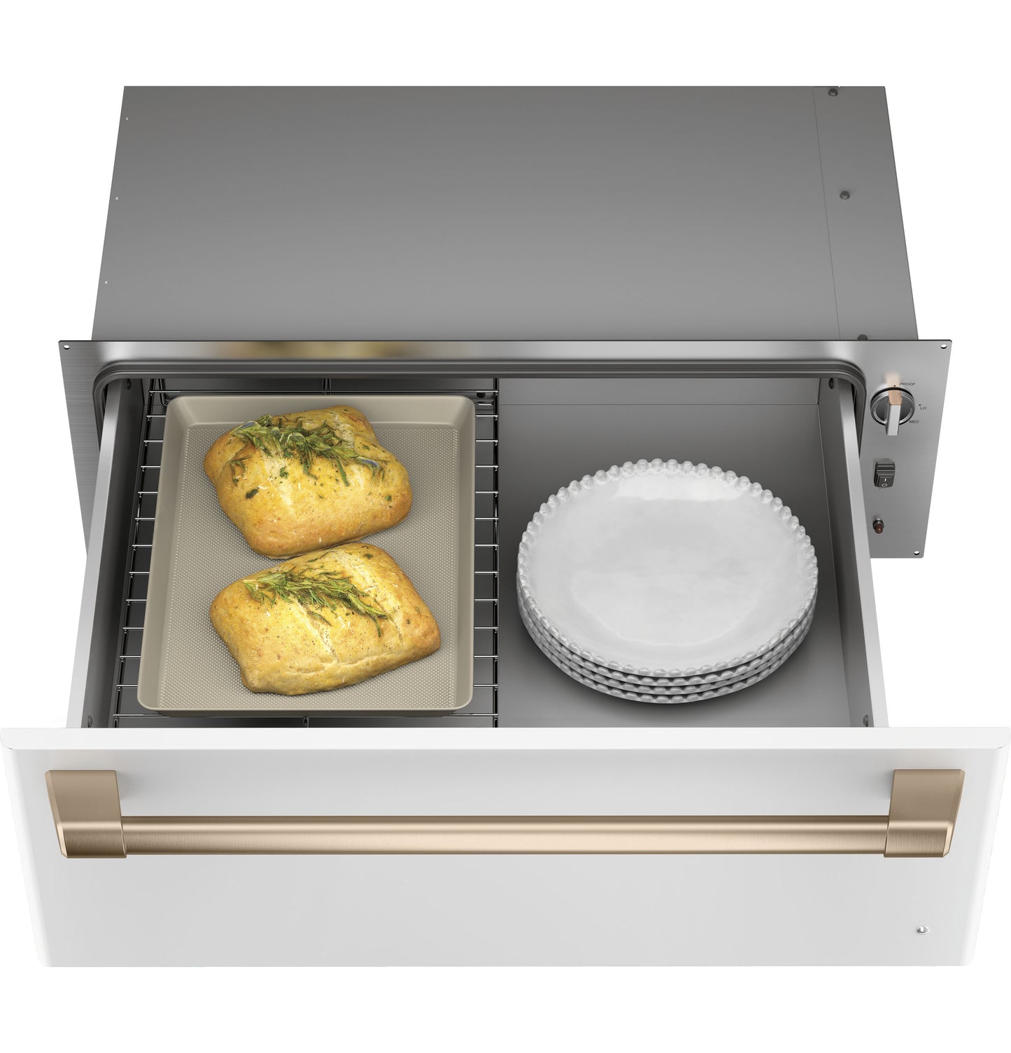 White warming drawer with brass handle in kitchen appliances setting, holding baked bread and stacked plates from wall ovens collection