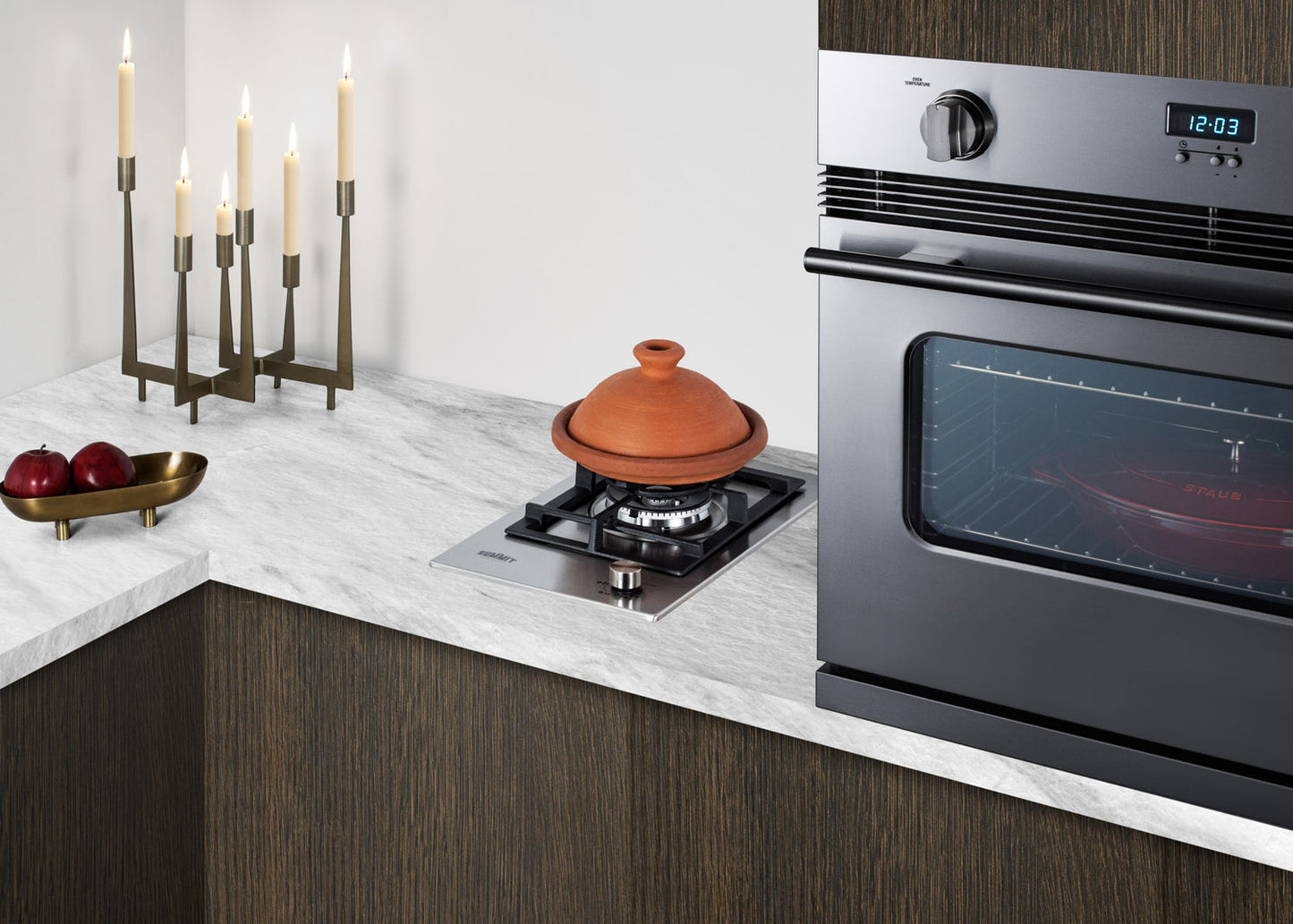 Compact stainless steel single-burner cooktop installed on marble countertop in modern kitchen setting with built-in oven