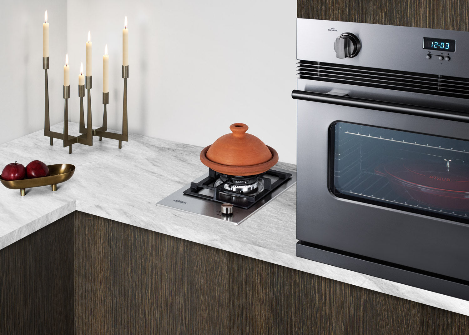 Compact stainless steel single-burner cooktop installed on marble countertop in modern kitchen setting with built-in oven